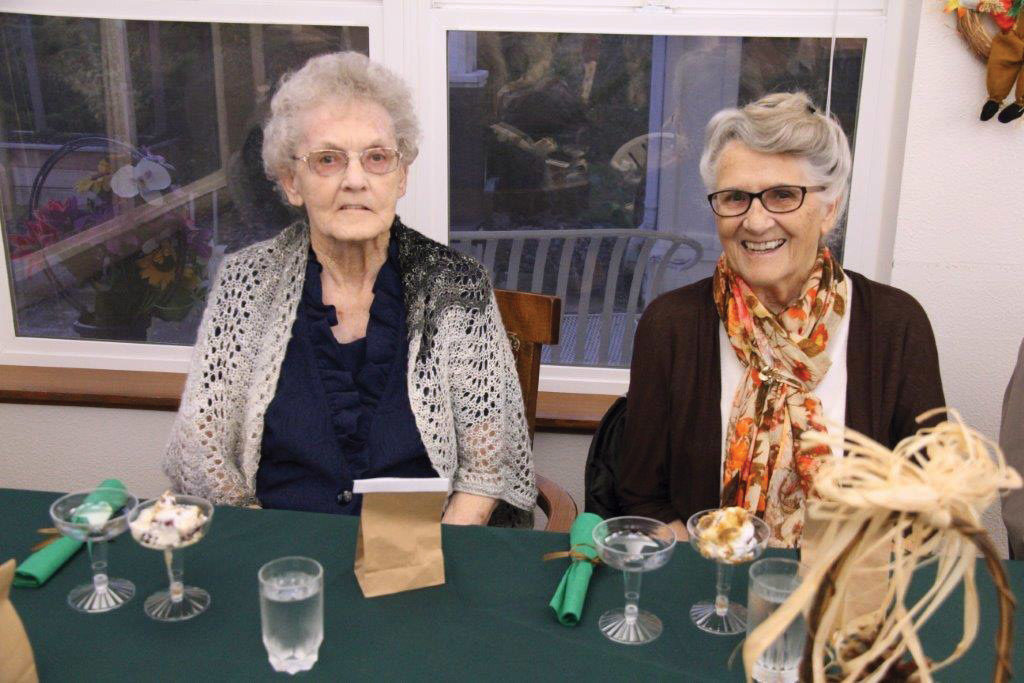 Two elderly women sitting at a table on Thanksgiving - Adams House Assisted Living